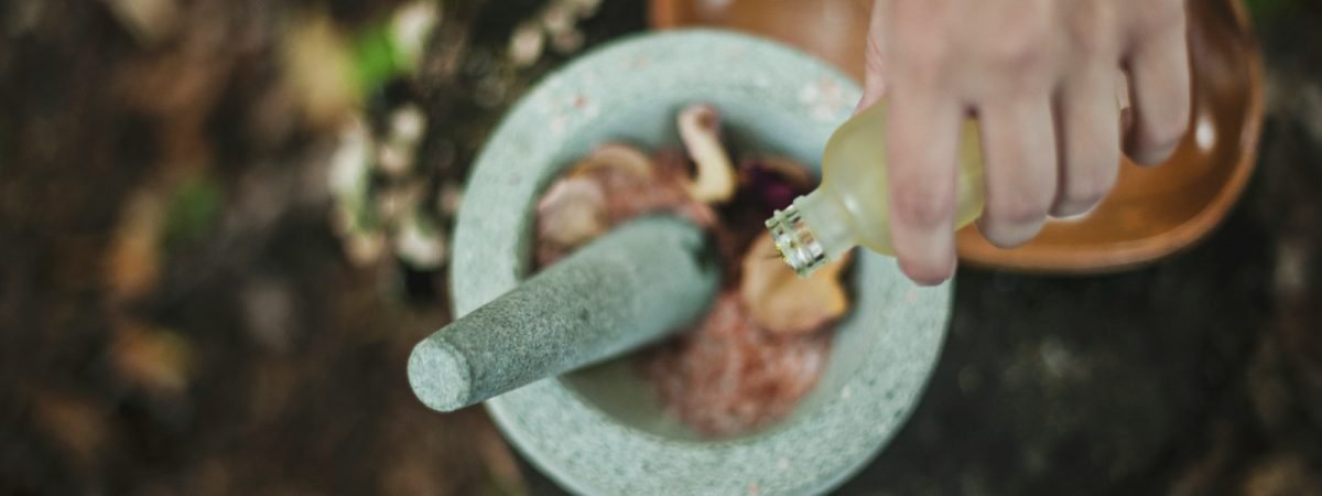 high angle photo of person pouring liquid from bottle inside mortar and pestle